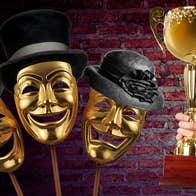 3 gold face masks laughing or crying wearing black formal hats beside hand holding up a large gold trophy