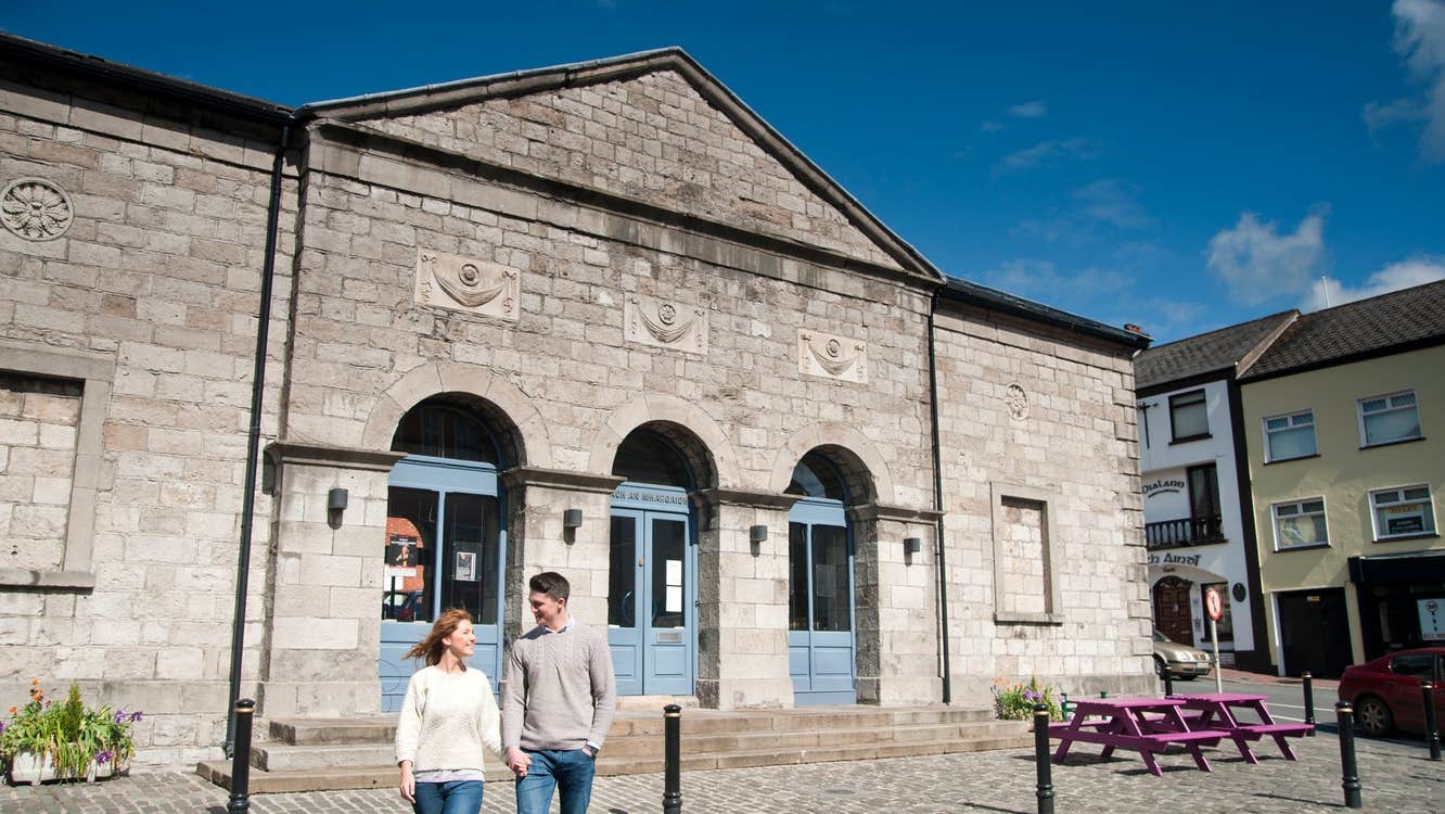 Two people walking along a street by a historic building
