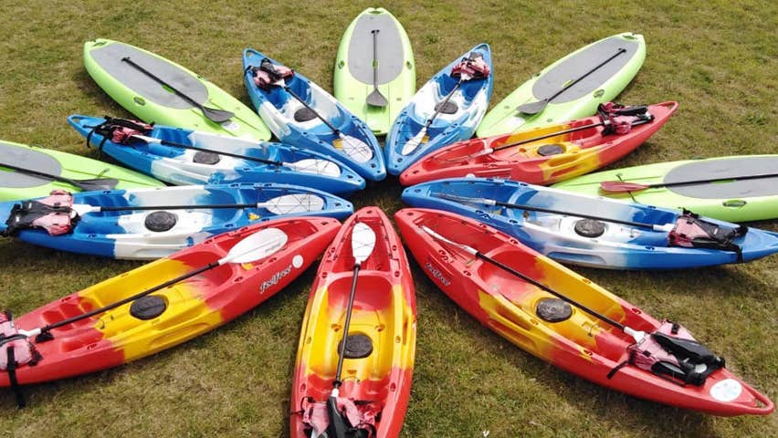 Kayaks and paddleboards laid out on the ground in a star shape