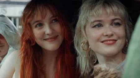 2 smiling women seated in a car, both looking in the same direction