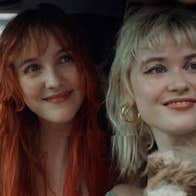 2 smiling women seated in a car, both looking in the same direction