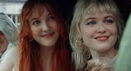 2 smiling women seated in a car, both looking in the same direction