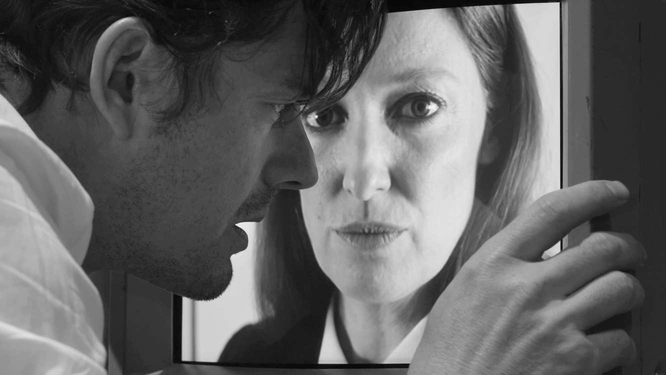 A man is looking closely at an image of a woman's face.