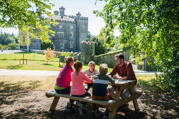 A family sitting at a picnic table on the grounds of Slane Castle