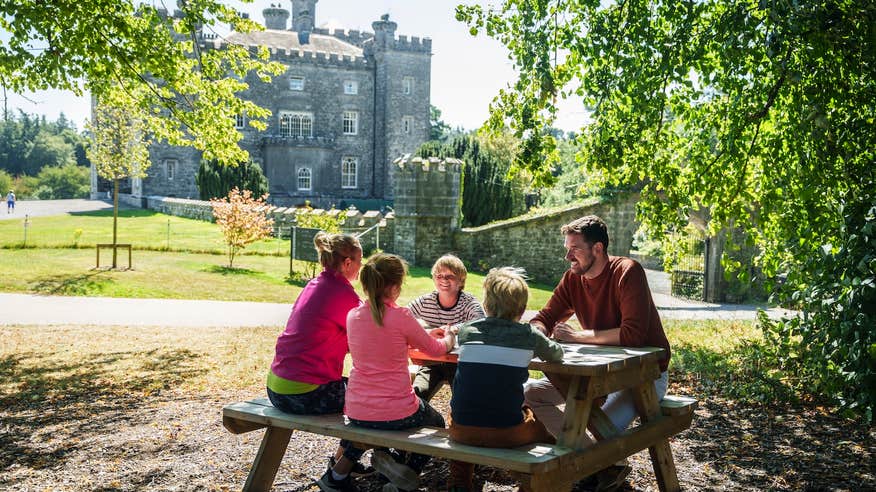 A family sitting at a picnic table on the grounds of Slane Castle