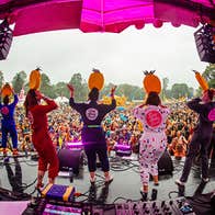 Sing Along Social Gleneagle rear view of people performing on a small outdoor stage with large audience in the background.