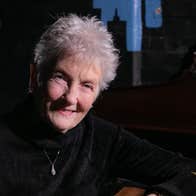 A smiling elderly woman in dark jumper