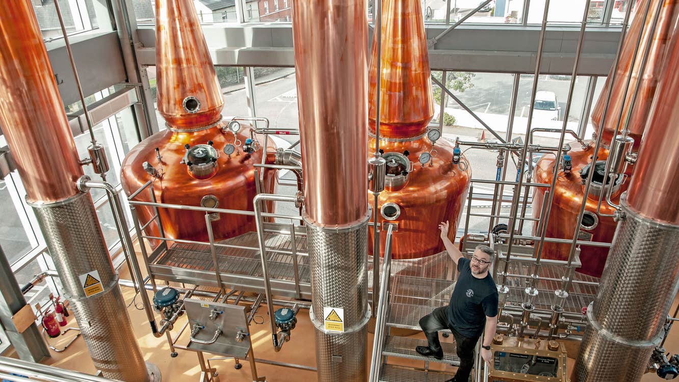 Clonakilty Distillery showing a guide in front of three copper stills