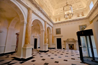 A large hall way in a Georgian house with marble floors and high arched ceiling