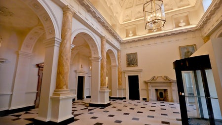 A large hall way in a Georgian house with marble floors and high arched ceiling