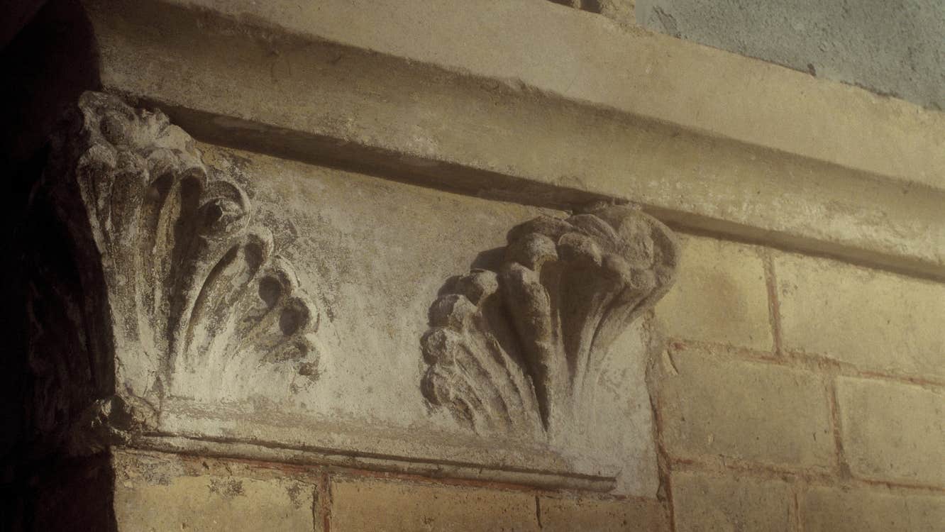 Part of an old, worn building with ornate sculpting.