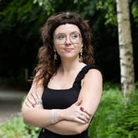 A smiling Ava Hayes is standing outdoors with her arms crossed.