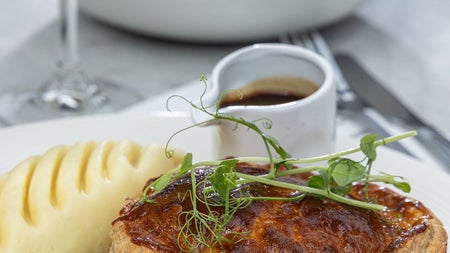 A pie served with peas mash potatoes and a glass of red wine