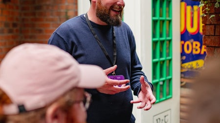 A tour guide standing beside an old fashioned phone box while speaking to a tour group