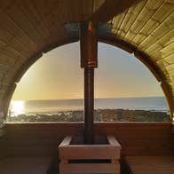 Sunset from inside The Hot Pod sauna looking out on Clonea Strand and the water in Waterford.