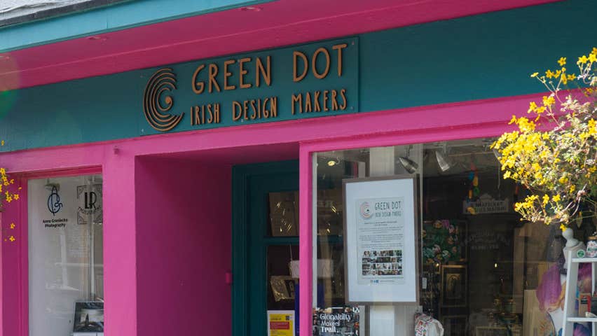 Pink and green coloured shop front with hanging baskets of flowers