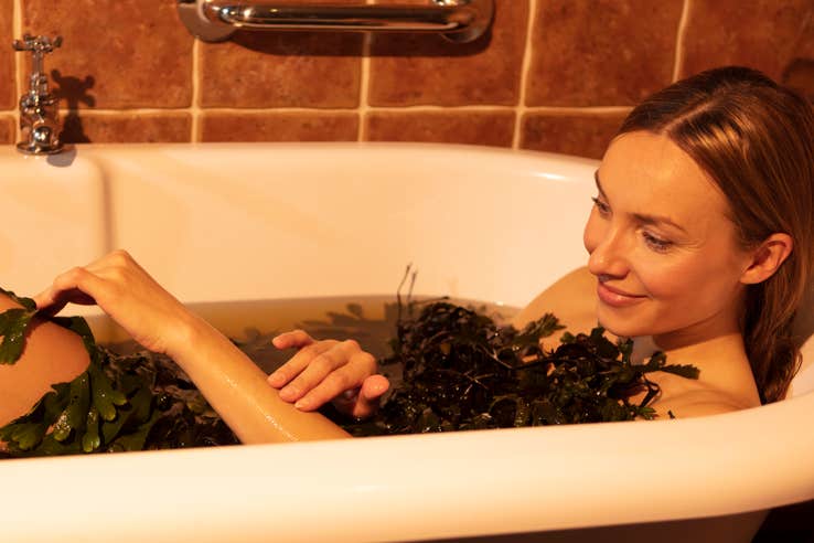 A woman relaxing in a seaweed candle-lit bath 