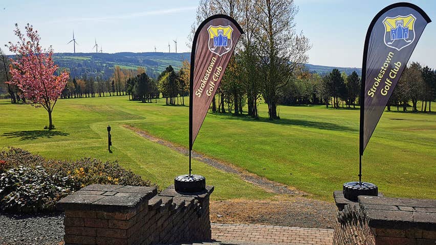 Image of two banner flags at the entrance to Strokestown Golf club with golf course in the background