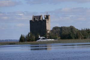 A castle on the lake with a boat passing by Secret Escapes Ireland, Clare