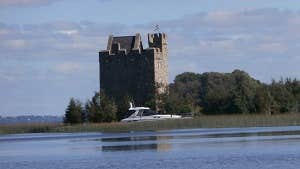 A castle on the lake with a boat passing by Secret Escapes Ireland, Clare