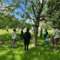 A group of people standing by a large tree