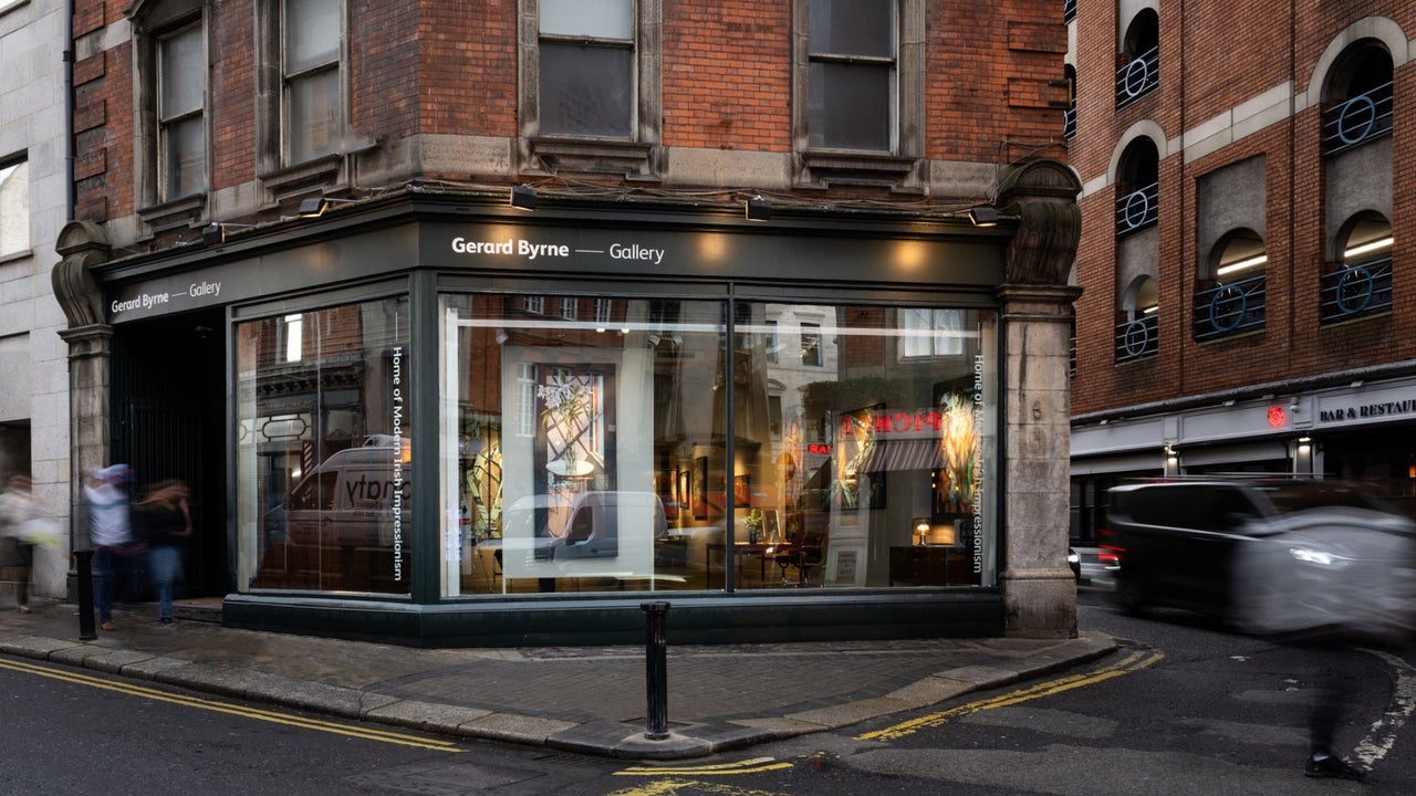 The exterior of a gallery with a black shopfront on a red brick building