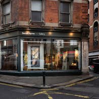 The exterior of a gallery with a black shopfront on a red brick building
