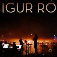 Band SIGUS RÓS with The Ulster Orchestra, dimly lit view of an orchestra and conductor on a stage with orange lights