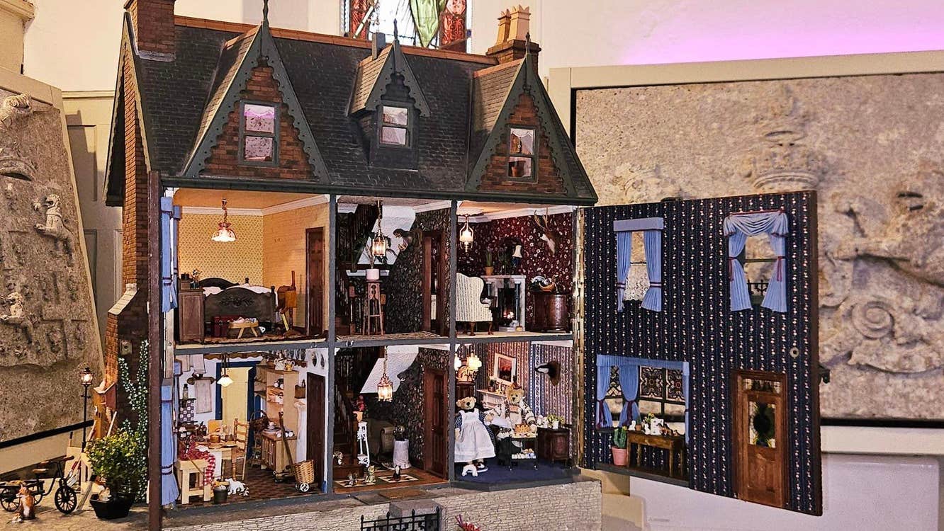 View of a large dolls house with open doors and 6 rooms full of miniature furniture.