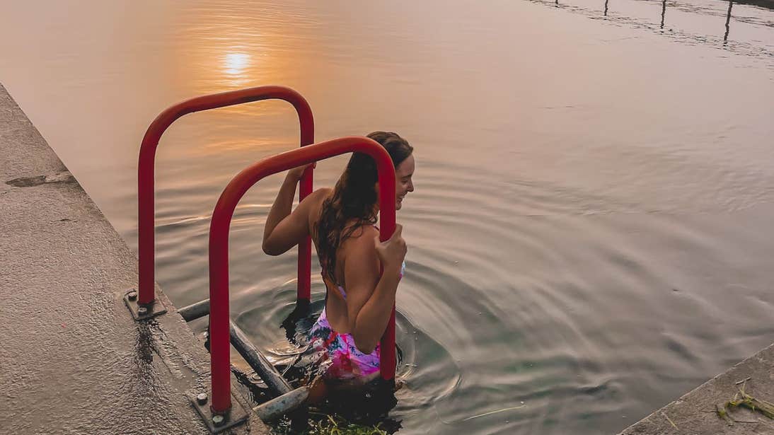 Roz Purcell standing in the water at sunrise in Banagher Outdoor Swimming Pool, Offaly