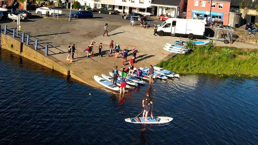 A group of people receiving tuition on paddle boarding on Lough Conn