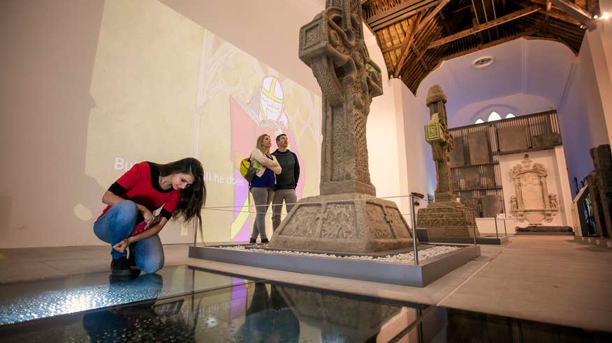 Three people observing the religious relics on display at the Medieval Mile Museum in County Kilkenny.