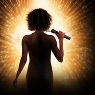 Silhouette of woman holding mic lit by halo of bright yellow light