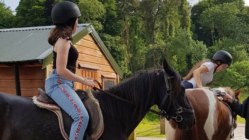 Two people on horseback and an instructor on foot speaking to them