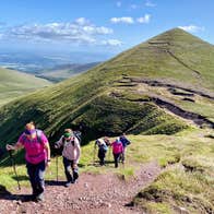 Five hikers walking up an ascent in single file