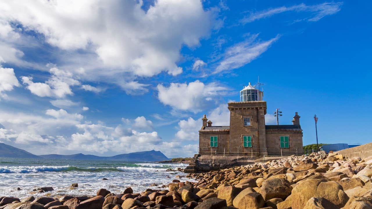 A small lighthouse beside a rocky coastline