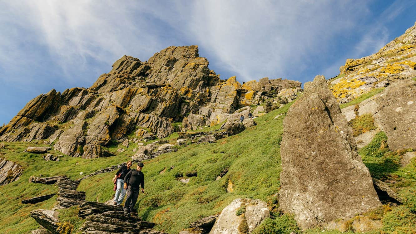 Two people walking down the ancient steps of Skellig Michael