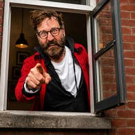 An angry looking man pointing a finger is at a small open window