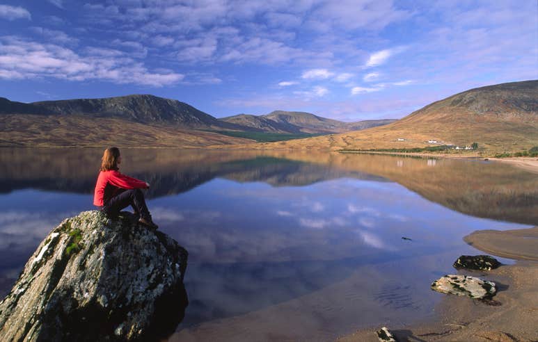 A hiker sitting beside Lough Feenagh along the Nephin Beg Mountains in Mayo