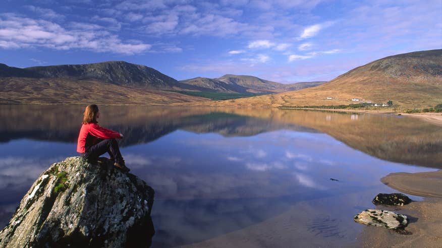 A hiker sitting beside Lough Feenagh along the Nephin Beg Mountains in Mayo