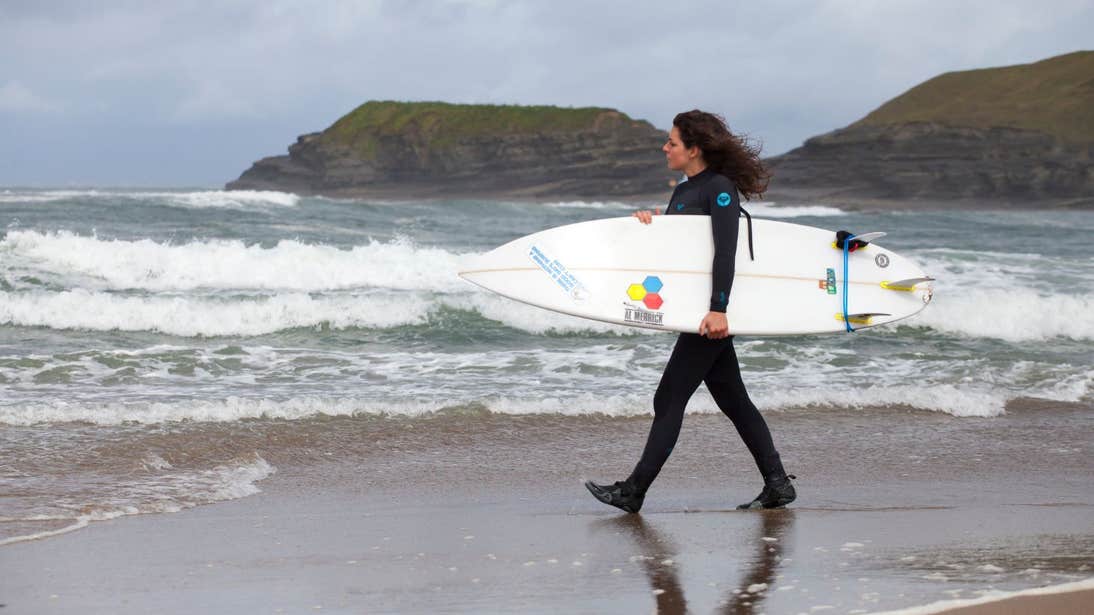 A woman wearing a wetsuit and heading towards the waves at Bundoran