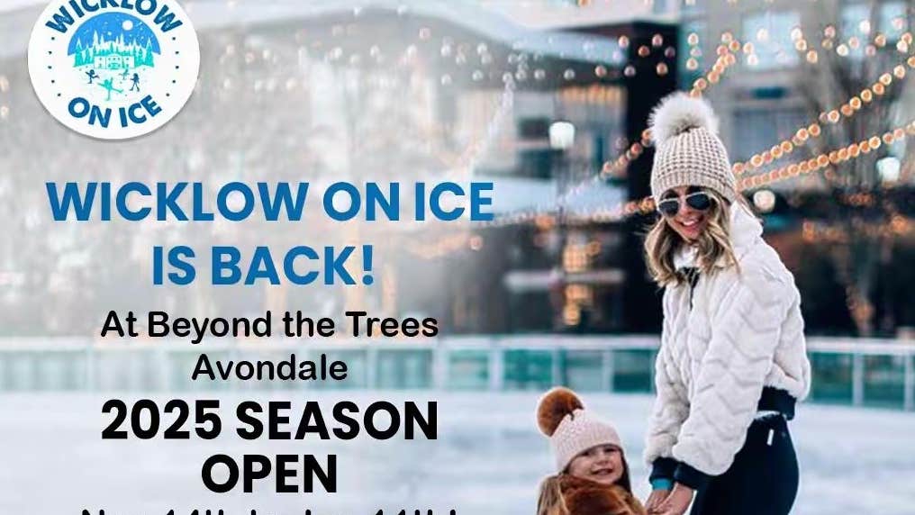 A adult and small child on an ice rink in wooly hats.