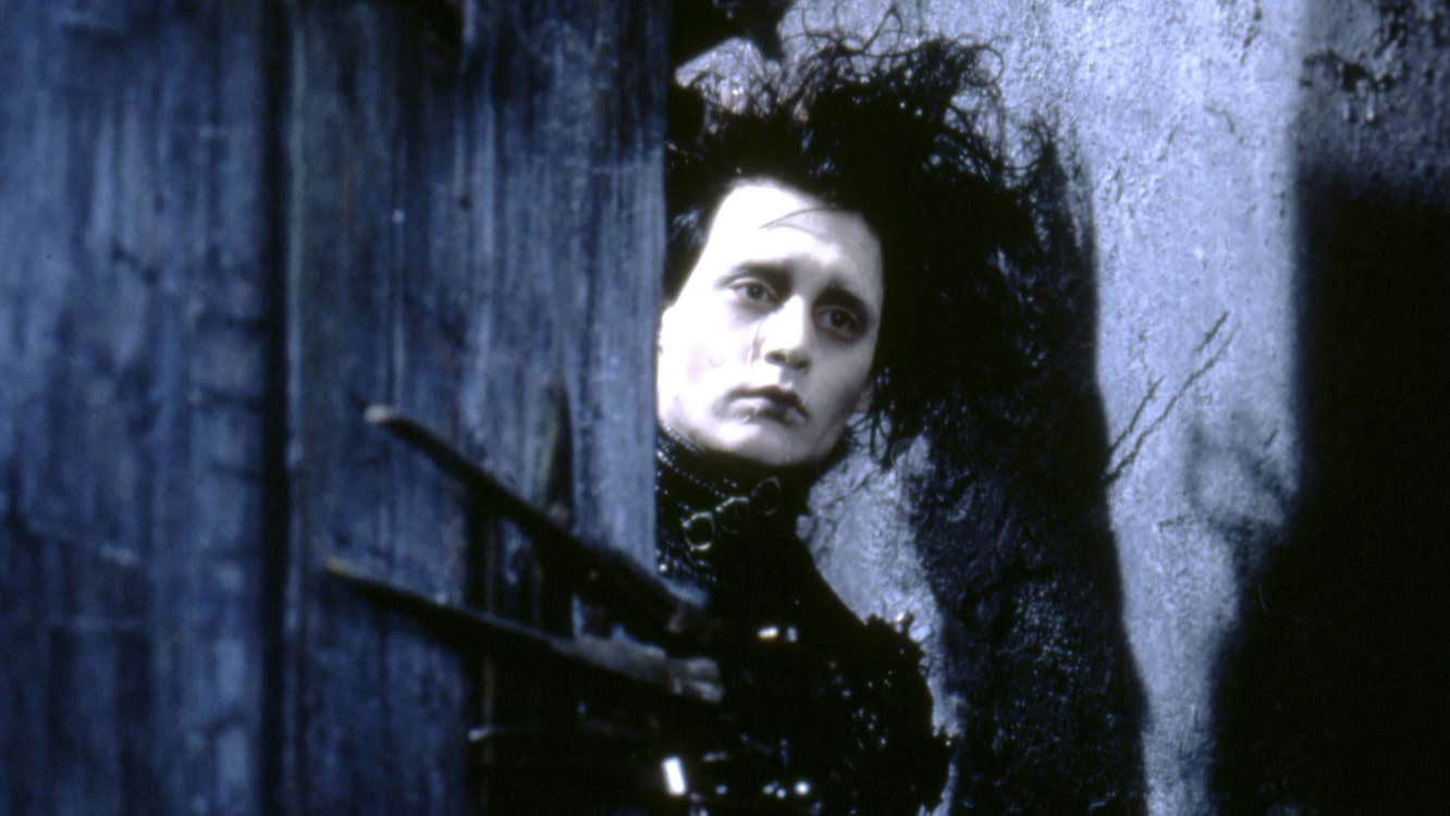 Edward Scissorhands is holding open a door. His has a sad expression.