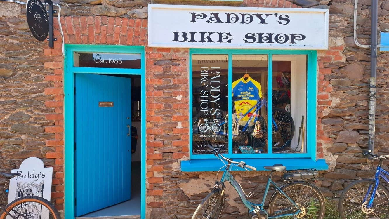 Red brick exterior of a shop with a blue door and bikes outside