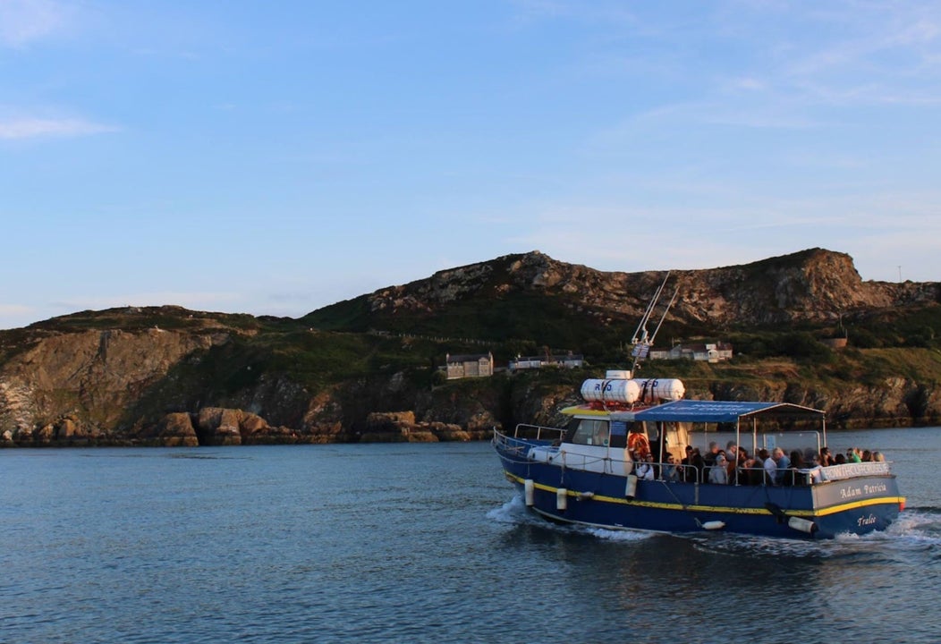 Blue boat on the water with cliffs in the background