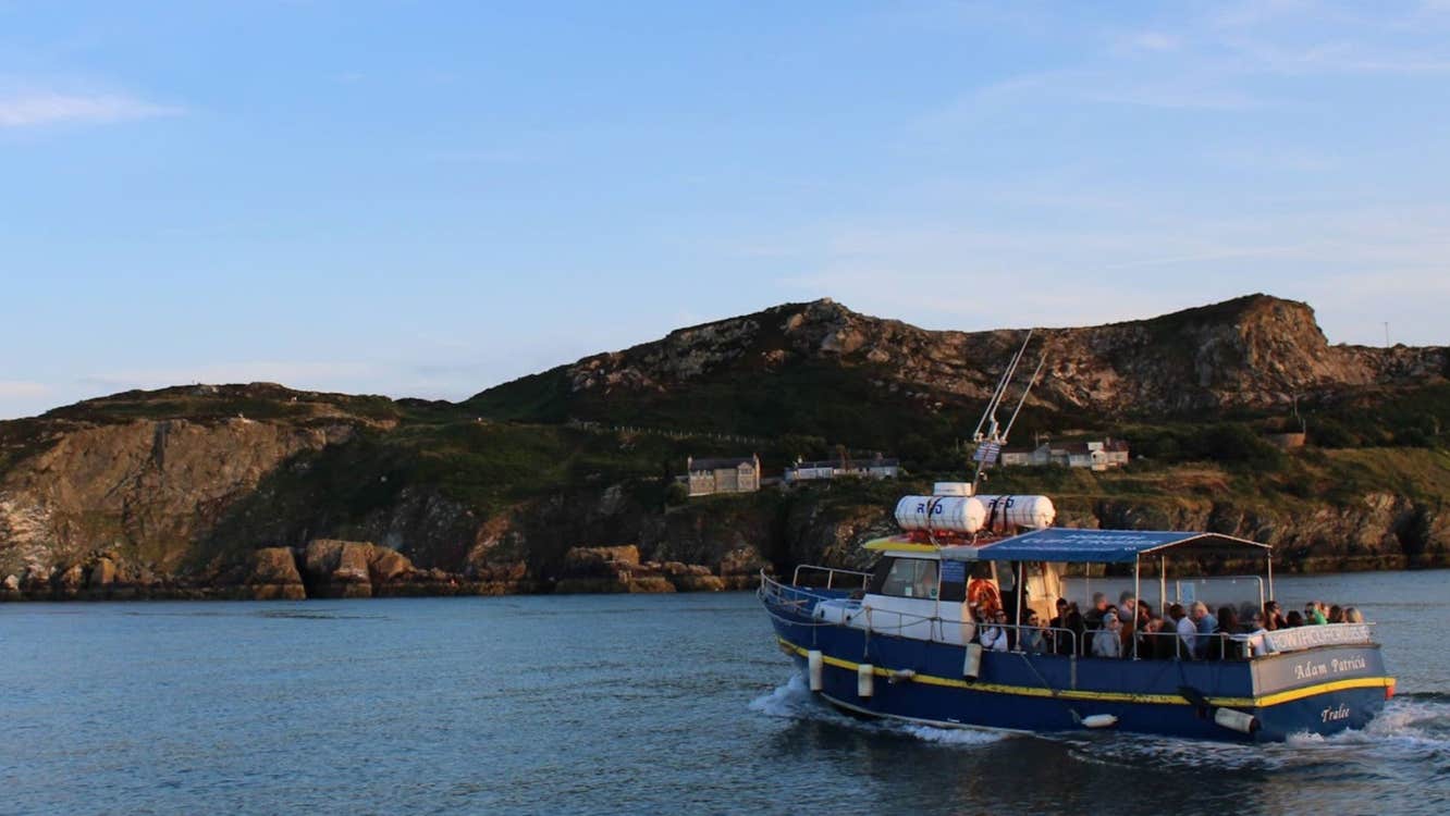 Blue boat on the water with cliffs in the background