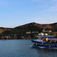 Blue boat on the water with cliffs in the background