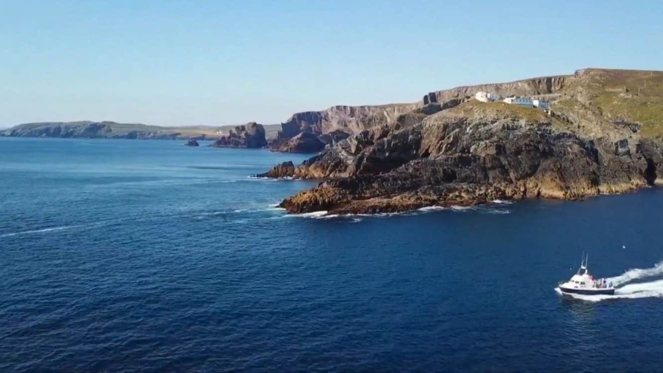A boat sailing past a headland
