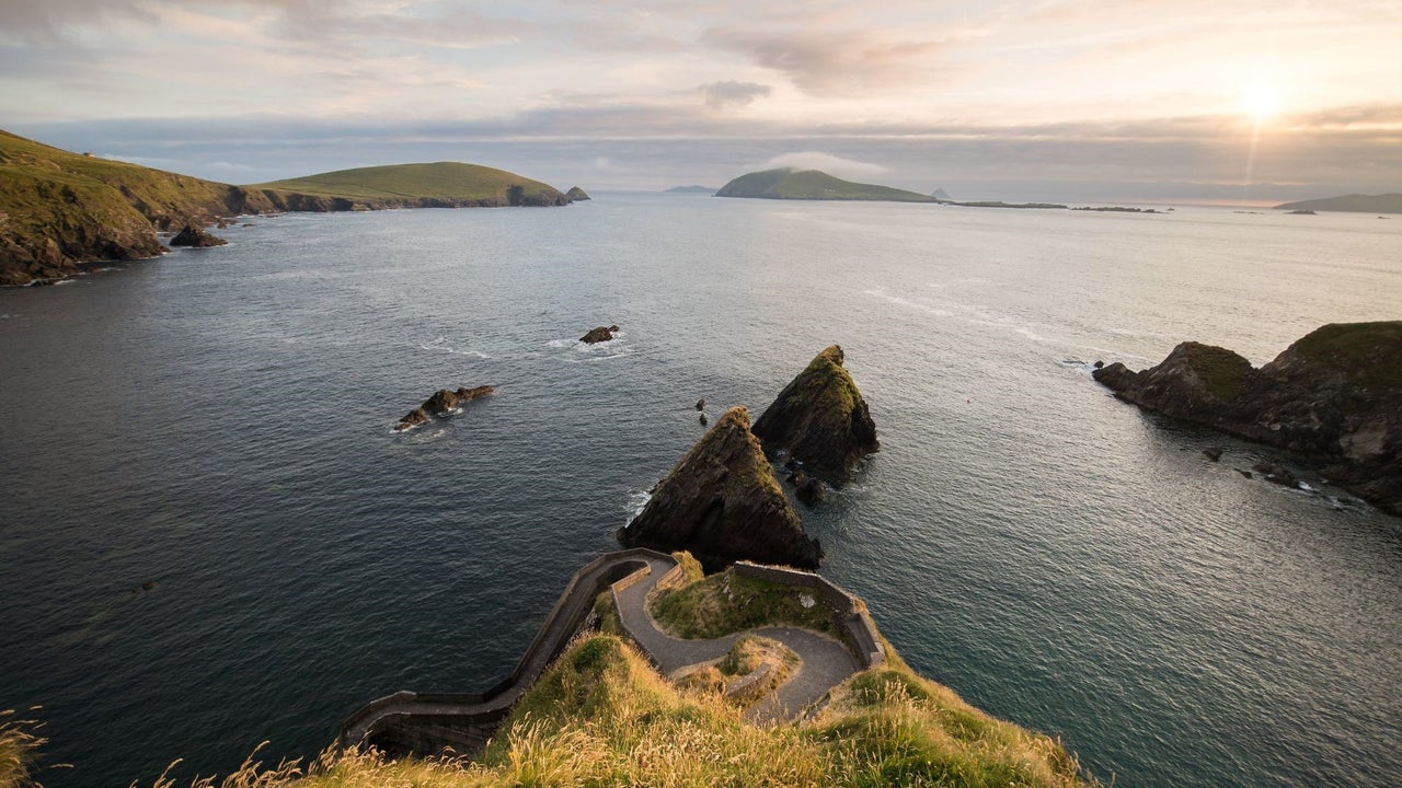 View of a pathway facing the sea with hills in the background