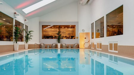 Swimming pool with wicker chairs and tables at the edge and plants